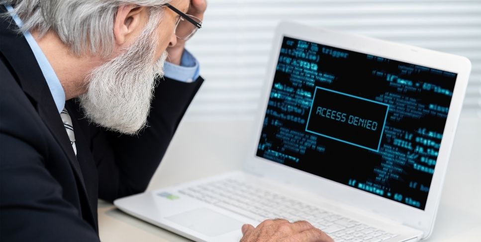 Older adult looking at a computer with access denied on the screen