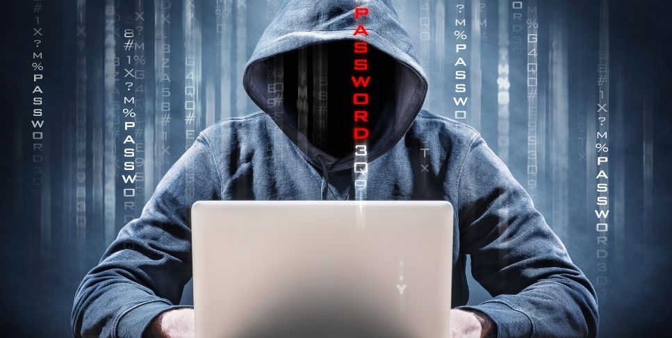 Faceless person in dark hoodie using a laptop