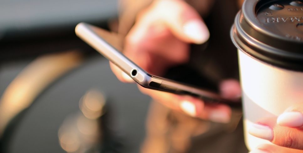 Person holding coffee and phone