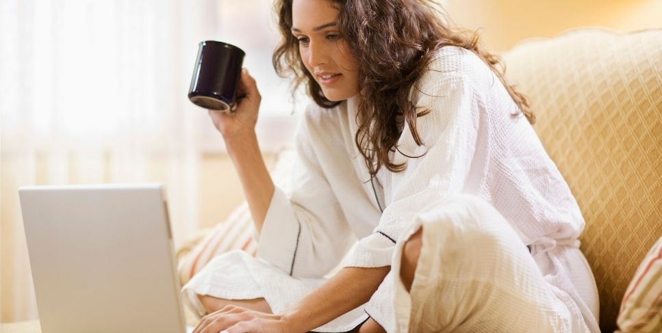 Woman drinking coffee and looking at computer