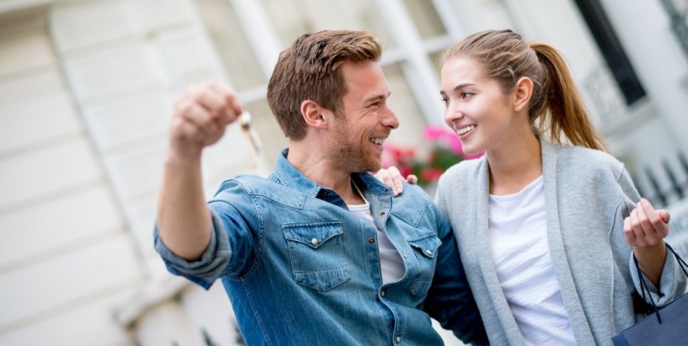 Couple holding key to new house